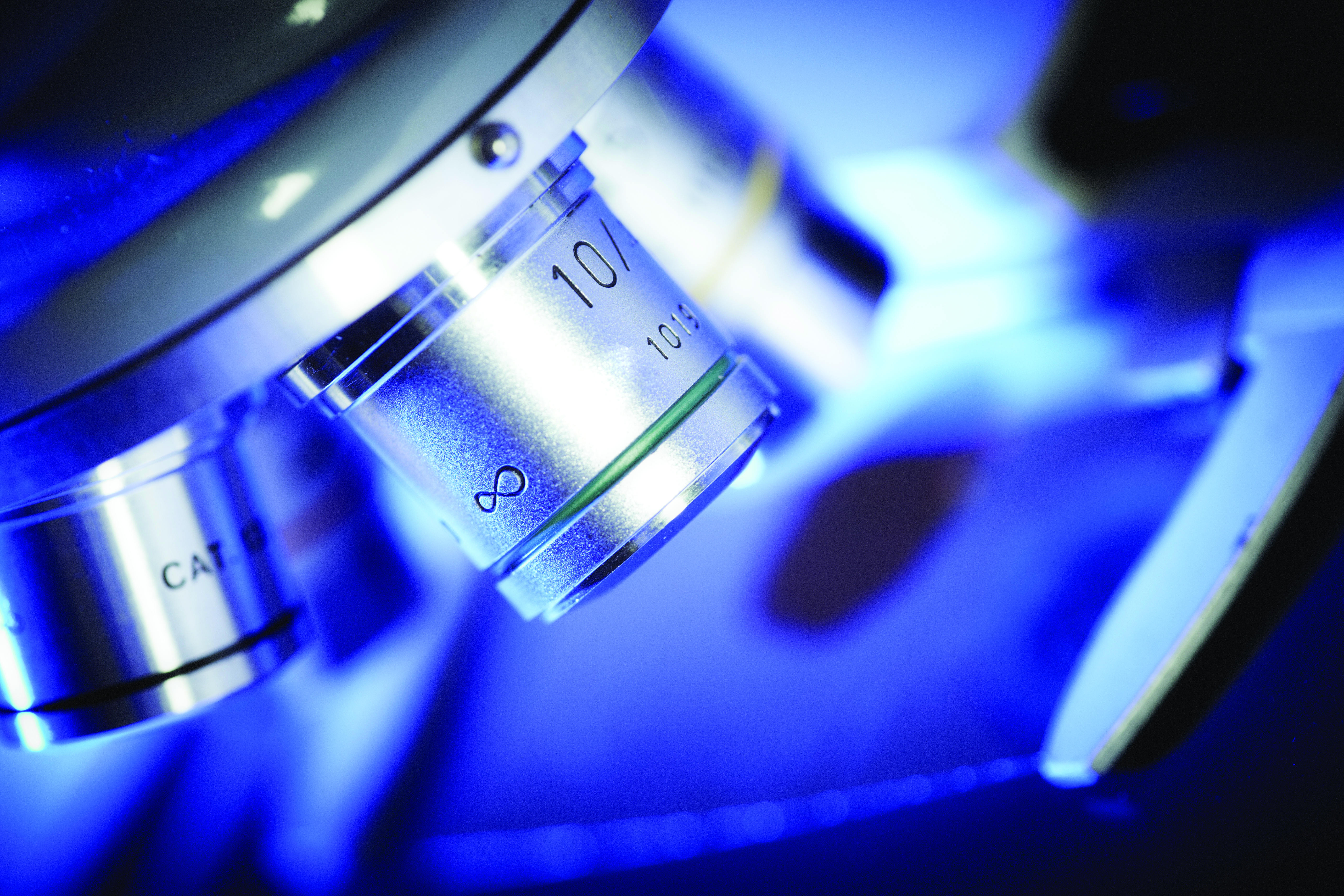 Close-up of a microscope objective lens used to examine cells for biomedical and cell manufacturing research.